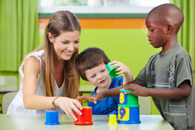 nursery teacher building tower with children in a kindergarten